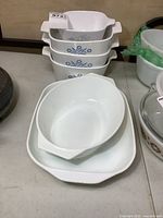 Stack of three CorningWare Cornflower Blue casseroles, additional CorningWare dish nested inside and Pyrex glass casserole visible to right