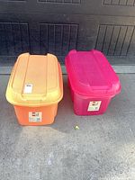 Front view of orange and pink 70 L totes with lids