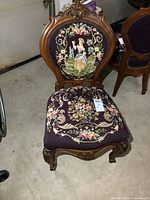 Front view showing carved wood frame and needlepoint backrest and seat