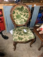 Front view of carved wood chair with green floral upholstery