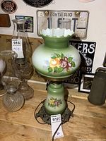 Full view of lamp showing green glass shade with roses, chimney and metal base