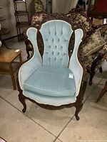 Front view showing carved crest with dove motifs and blue tufted upholstery