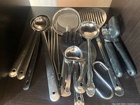 All utensils grouped together in cabinet showing variety and condition