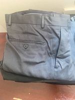 Folded grey-blue dress pants showing back welt pocket with button