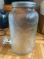 Embossed clear glass beverage dispenser showing lid, body pattern and spigot