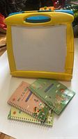 Yellow and blue plastic easel front with paper side and three copybooks