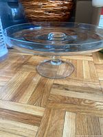 Side view of clear glass pedestal cake stand on wooden floor