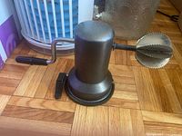 Side view of coconut grater showing crank handle, blade head and suction base