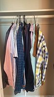 Eighteen shirts hanging in closet, showing variety of colours and patterns