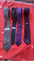 All four neckties laid out side by side showing colors, patterns and labels