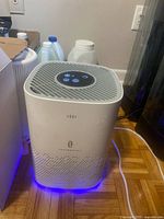 Front view of TaoTronics TT-AP006 air purifier plugged in with blue base light
