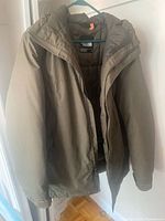 Full view of olive green The North Face hooded jacket on hanger