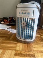 Front view of TIPTOP HOME evaporative air cooler showing brand name, buttons, grille, strap handle