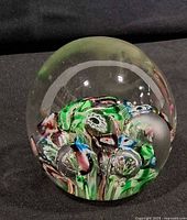 Front view of clear dome paperweight showing millefiori canes and two air bubbles