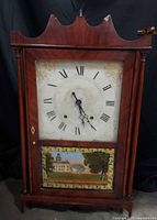 Front view of wooden shelf clock showing dial and painted lower glass