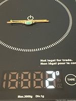 Full view of gold bar brooch on scale showing 2 g weight