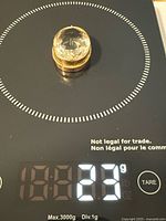Pendant on digital scale reading about 23.3 g