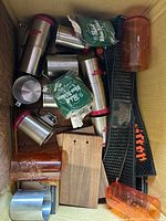 Top view of box showing stainless mugs, wrapped shot glasses, jigger, amber glasses, bar mat, wooden boards