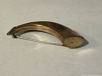 full view of curved pin showing gold tone and pin back