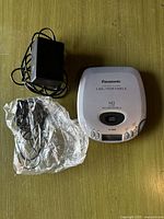 Top view of Panasonic portable CD player with AC adapter and earphones on green surface