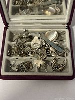 Overview of jewelry pieces in box showing variety of items and silver coloration.