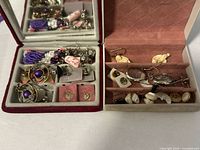 Two open jewellery boxes with assorted earrings and findings
