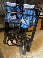 Folded black metal cart with blue fabric bags and four wheels