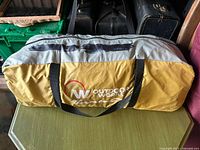 Yellow and gray Outdoor Works tent carry bag with logo visible