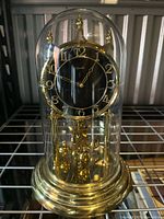 Full view of brass rotating clock with glass dome