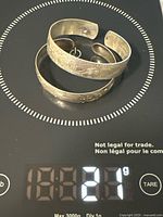 Two sterling cuff bracelets on scale showing weight