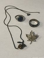 Group shot of all four sterling pieces: brooch, necklace, two rings