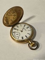 Closed hunter-case pocket watch with lid open displaying dial