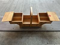 Full view of wooden cantilever sewing box opened, showing compartments and handle