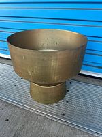 Side view of brass-tone metal pedestal planter