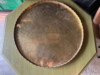 Front view of round brass tray on green table