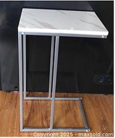 Full view of side table showing grey metal C-frame and white faux marble top