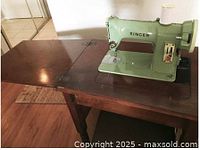 Singer 185J sewing machine mounted in wooden cabinet with leaf extended