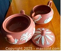 Open sugar bowl with lid removed alongside creamer showing interior and relief decoration