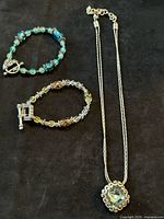 Necklace and two bracelets arranged on black background