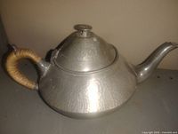 Right side view of hammered pewter teapot showing overall shape, spout and wrapped handle