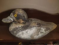Left side view of wooden duck decoy showing head, body shape and worn paint