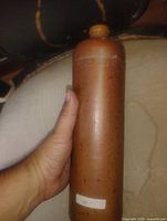 Full view of brown cylindrical stoneware bottle held in hand