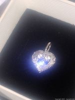 Heart-shaped sterling silver pendant with three clear stones displayed in box