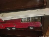 Side view showing red metal body, six wheels, white ladder