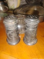 Front view of both pewter shakers and glass flower frog