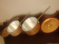 Pair of copper saucepans interior view showing stainless lining and brass handles