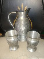 Pitcher and two mugs front view showing relief artwork
