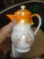 Front view of porcelain chocolate pot with lid showing floral design