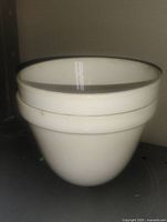 Two white pottery bowls nested together, side view