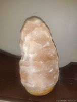 Front view of pink Himalayan salt lamp on wooden base